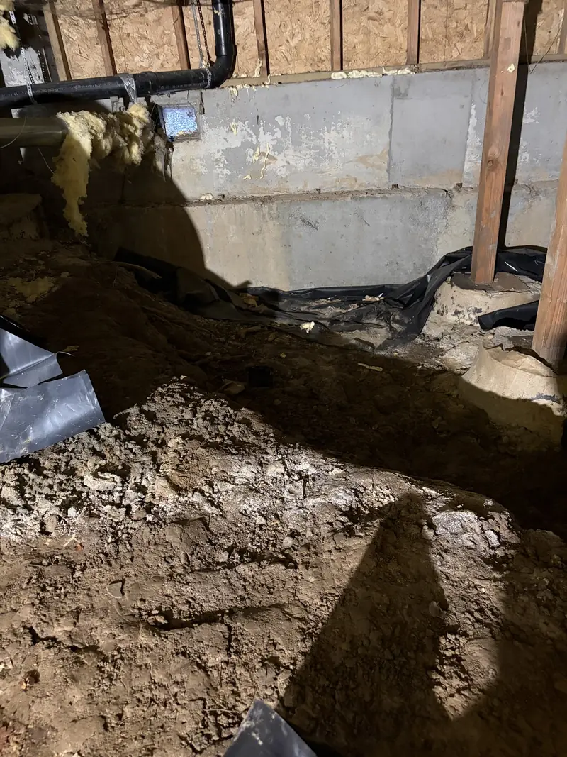 Excavated soil along a crawl space foundation wall