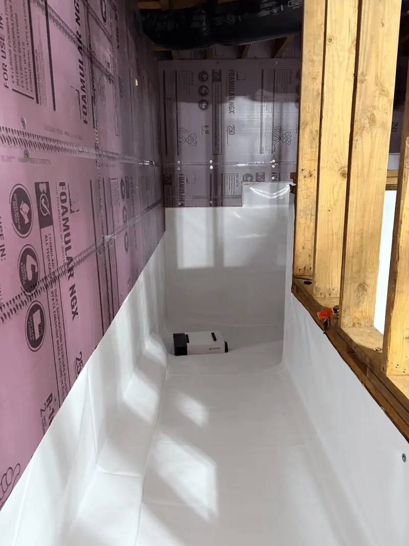 Encapsulated crawl space with a white liner on the floor and insulation board on the foundation walls