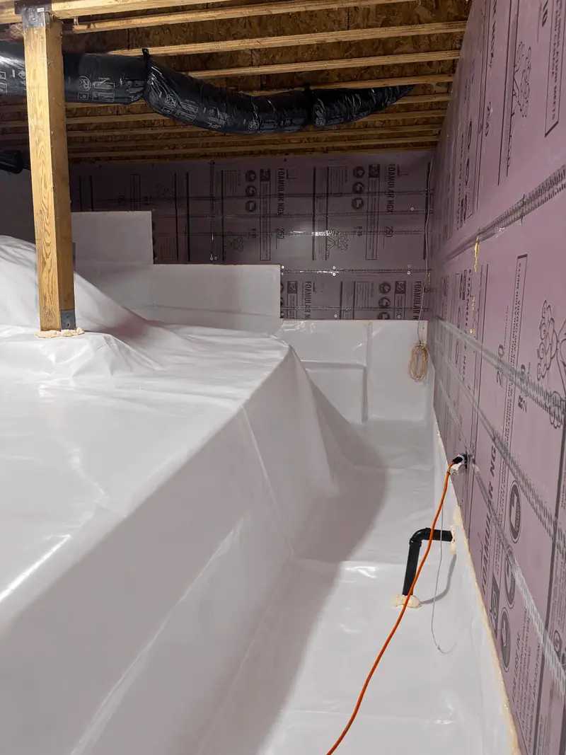 White crawl space liner wrapped up the foundation walls and over a raised footing
