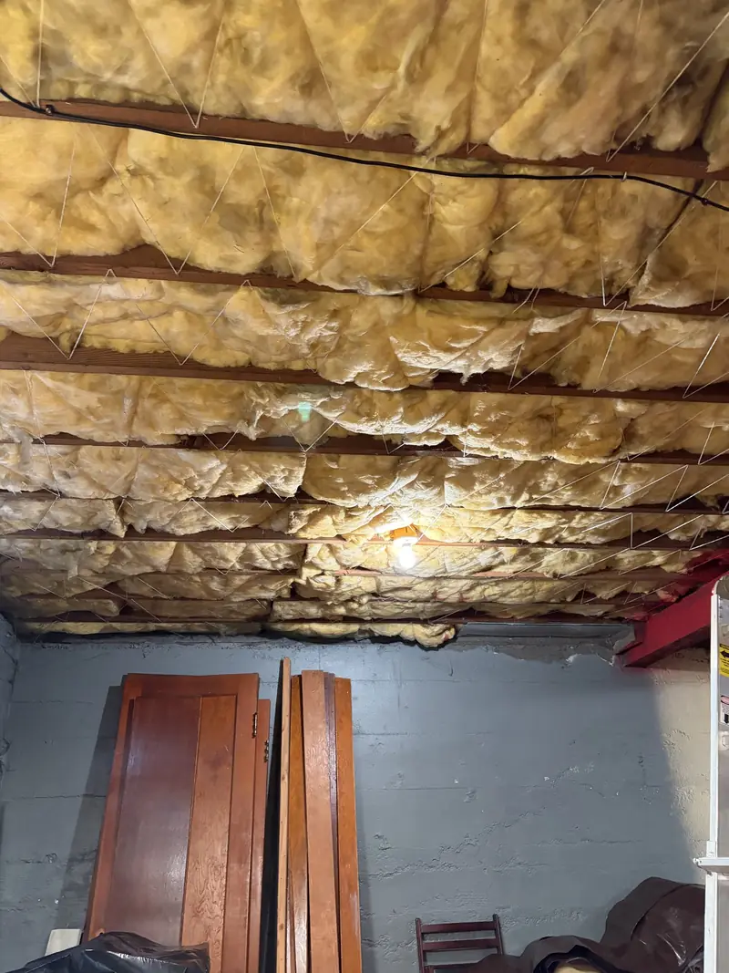 New fiberglass insulation installed between wood floor joists
